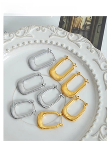 Macro di orecchini a U in oro e argento con trama verticale su un piatto bianco