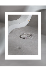 Detail of lava texture silver ring with a tiny pink zircon on a minimalist background