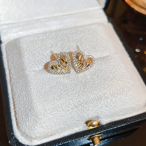 Macro view of gold heart stud earrings featuring radiant textures and zircon inlay
