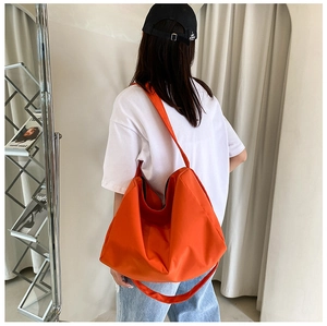Large bright orange oxford shoulder bag shown on model for daily commuting style