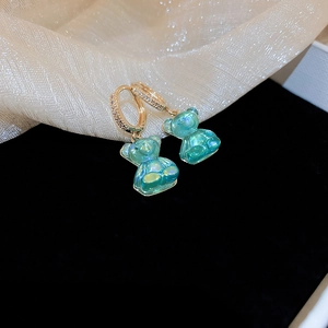 Détail des boucles d'oreilles ours en résine avec cristaux étincelants et fini doré