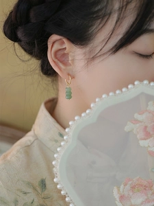 Detail view of gold hoop earrings with green aventurine beads on a model wearing silk