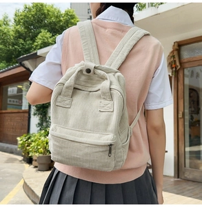 Nahaufnahme eines beigen Cord-Rucksacks mit Front-Reißverschluss und Tragegriff oben