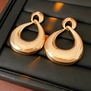 Detail of hollow waterdrop earrings in gold finish resting on black leather box