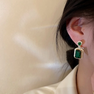 Boucles d'oreilles vintage en cristal vert émeraude avec monture dorée sur modèle