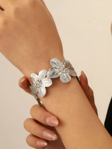 Close-up of a silver flower bracelet with wrinkled texture on a female wrist