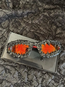Detail of avant-garde sunglasses with black textured frames and bright orange lenses