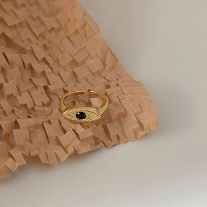 Detailed view of adjustable golden evil eye ring with black gemstone on honeycomb paper