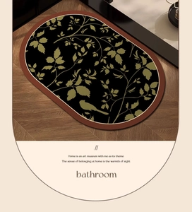 Macro shot of oval bathroom mat showing green leaf and bird patterns on dark base