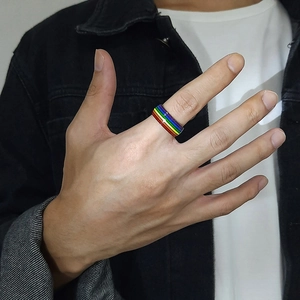 Detail of a rainbow enamel titanium steel ring worn on a finger for unisex style