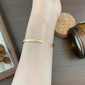 Detail of gold hammered texture on an open cuff bracelet worn on a wrist