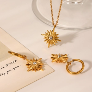 Close-up of golden starburst necklace and hoop earrings set with sparkling crystals