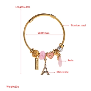 Detailed view of gold and pink bracelet with Eiffel Tower and heart charms and measurements