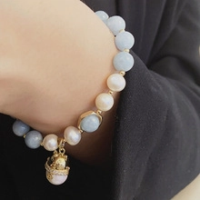 Detail of freshwater pearl bracelet with blue beads and a lucky cat gold charm