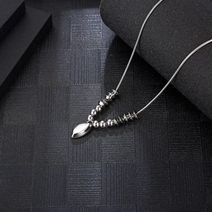 Detail of silver snake chain necklace with geometric beads and irregular metal pendant