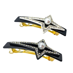 Detalle de horquillas de estrella de lujo con perlas y strass sobre base negra brillante
