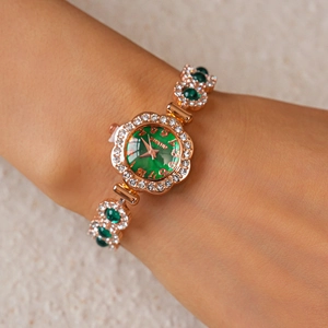 Close-up of a luxury gold-tone watch with a green dial and sparkling rhinestones on the wrist