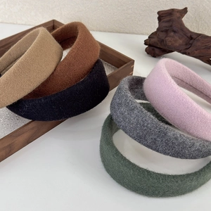 Set of six colorful wool felt headbands in neutral tones on a rustic wooden tray