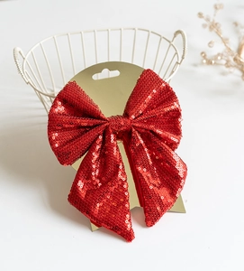 Close-up of a festive red sequined bow ornament on a gold card for Christmas decor