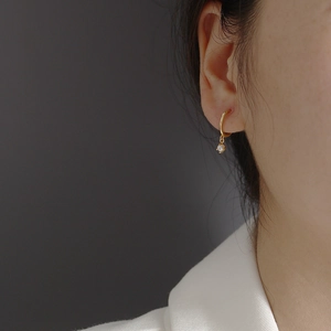 Close-up of elegant gold hoop earrings with small white pearl charms worn on ear