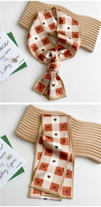Close-up of orange checkerboard silk scarf with heart patterns and hand-rolled edges