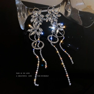 Sparkling silver flower tassel earrings with crystals on a glass cup background