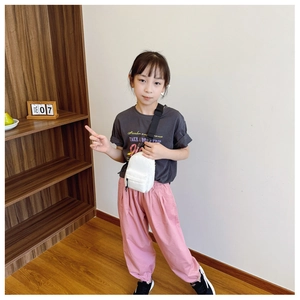 Close-up of white nylon chest bag worn by a child in a minimalist indoor setting