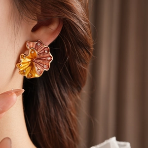 Macro detail of vintage metal flower earring with crystal accents and enamel finish