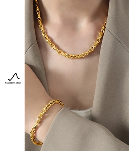 Detailed close-up of gold-plated stainless steel necklace and bracelet set on a model
