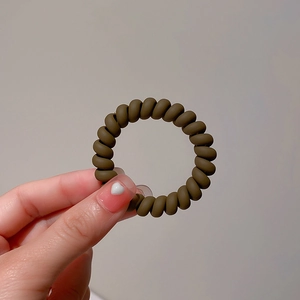 Detail of dark brown spiral telephone wire hair tie held by hand for elasticity