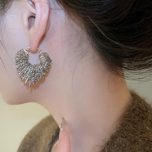 Detailed close-up of grey crystal beaded heart earrings worn by a model in soft lighting