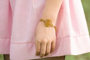 Detail of a gold Hamsa palm pendant on a double-layer titanium steel bracelet for women
