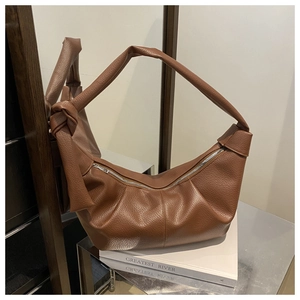 Detail of a brown crescent bag with pleated litchi leather and knotted wide strap