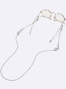 Close-up of elegant eyewear chain with polished white pearls on silver metal links