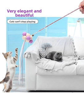 Pink wand cat toy with macaron plush balls and ribbons in a domestic setting