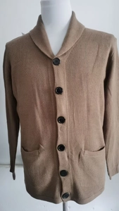 Detail view of camel knit cardigan showing black buttons, shawl collar, and dual pockets