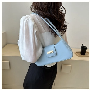 Back view of a model wearing a light blue faux leather baguette bag with gold metal buckle