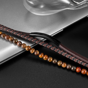 Detail of woven leather bracelet with tiger eye stone beads on a dark textured surface