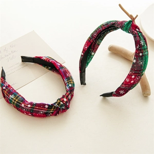 Detail of red and green plaid Christmas knotted headbands with white snowflake prints