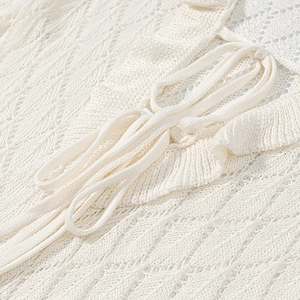 Detailed macro view of the white lace dress showing intricate crochet and ribbon tie design