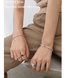 Detail showing layers of gold and silver tennis bracelets with zircon stones on wrist
