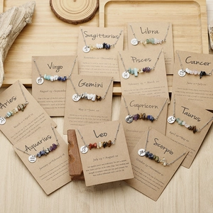 12 Zodiac natural crushed stone necklaces on wooden tray with astrology backcards