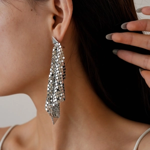 Macro shot of silver metallic mesh tassel earrings with geometric triangle hardware