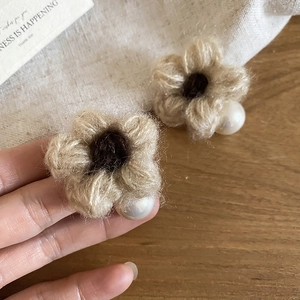 Detail shot of a handmade beige felt flower earring with white pearl decoration