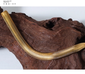 Close-up of golden flat snake bone chain showing detailed scale texture on wood