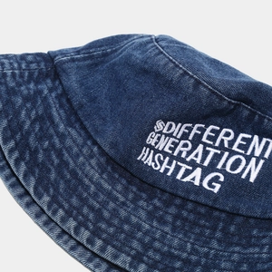 Close-up of blue denim bucket hat featuring white embroidery and vintage wash texture