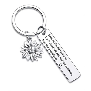 Macro view of sunflower charm and engraved stainless steel tag on a silver keychain