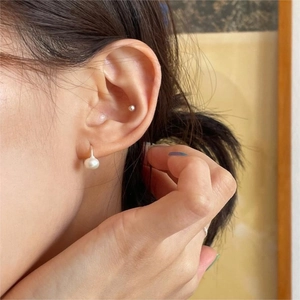 Close-up of model wearing elegant white freshwater pearl drop earrings with silver hooks
