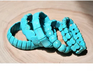 Detail of four-piece turquoise bead bracelet set with heart and leaf charms on wood