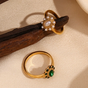 Detail of vintage 18K gold plated rings with pearls and emerald emerald gemstones